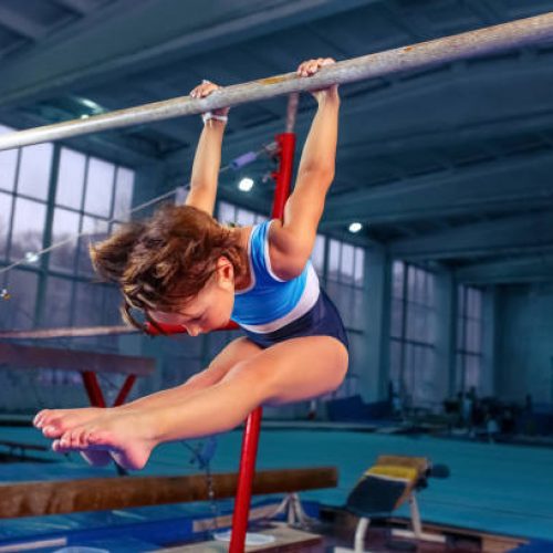 The beautiful little girl is engaged in sports gymnastics on a parallel bars at gym. The performance, sport, acrobat, acrobatic, exercise, training concept