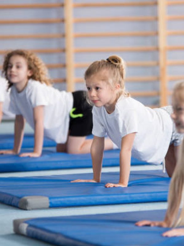 Happy girl exercising on blue mat during corrective gymnastics classes